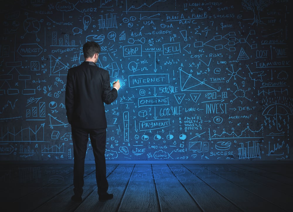 Businessman drawing business schemes on glass wall